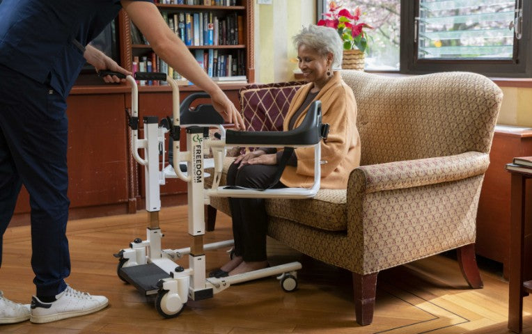 A nurse helps an older black patient into a Mobile Patient Lift
